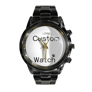 May include: A black metal wristwatch with a white dial featuring the text "LOGO Custom Watch" in black lettering. The watch has gold-toned hands, a date window at the four o'clock position, and a black link bracelet with a polished finish.