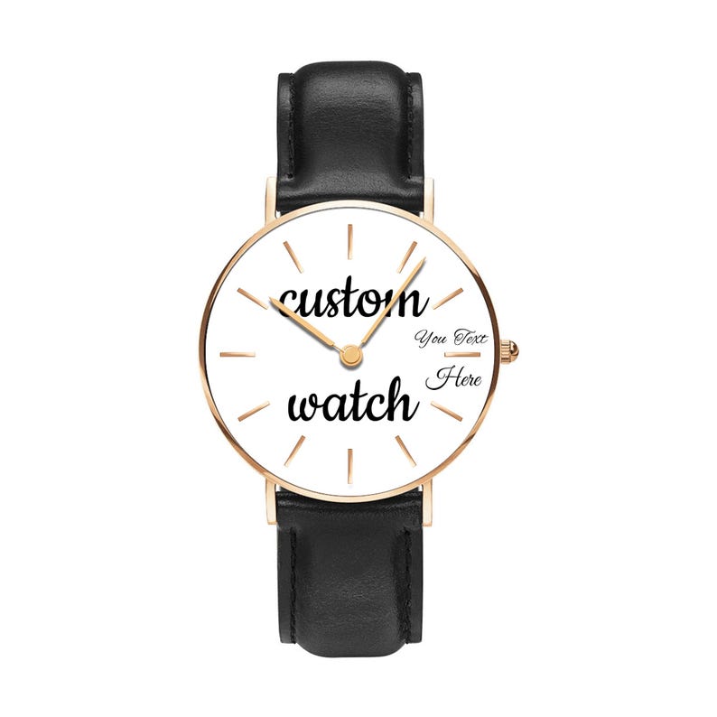 May include: A wristwatch with a black leather strap and a rose gold-toned circular case. The white watch face features thin gold-toned hour markers, gold-toned hands, and the black text "custom watch" with "You Text Here" printed on the right.