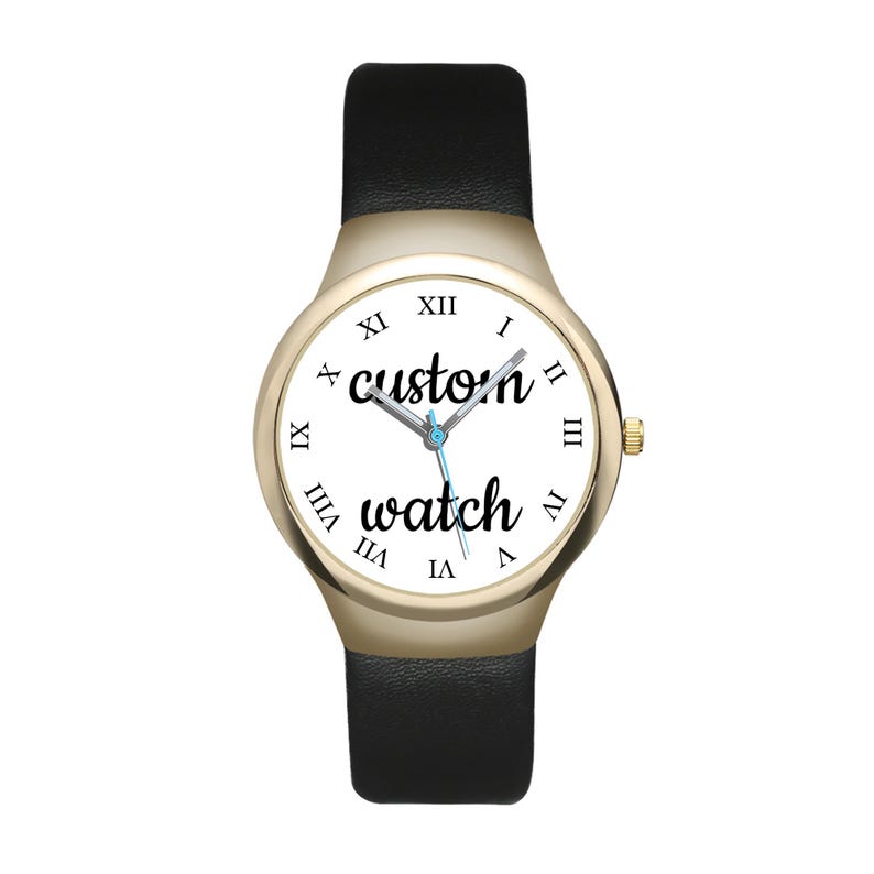 May include: A wristwatch with a gold-tone case and a black leather strap. The white dial features black Roman numerals and the text "custom watch" in a cursive script. The watch has silver-tone hour, minute, and second hands centred on the face.