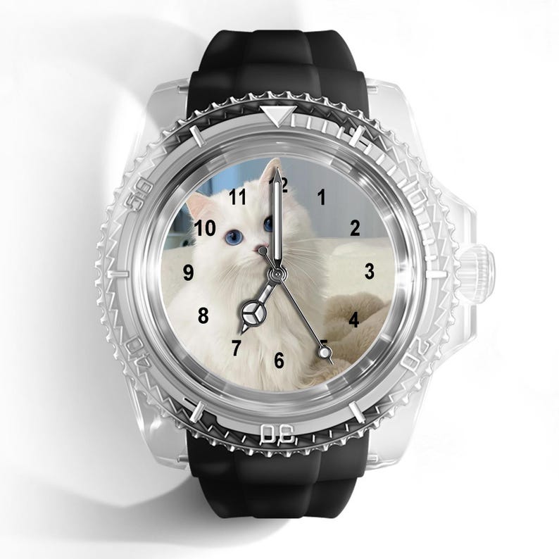 May include: A wristwatch featuring a black silicone strap and a clear, transparent casing. The watch face displays a high-resolution photograph of a fluffy white cat with blue eyes, overlaid with black Arabic numerals and silver-toned hands.