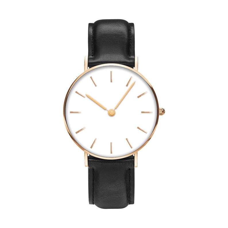May include: A wristwatch featuring a round rose gold case with a clean white dial, thin rose gold hour and minute hands, and simple line markers. The watch is attached to a smooth black leather strap with visible stitching and a metal buckle.
