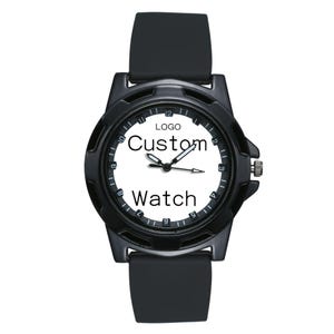 May include: A black wristwatch with a white face featuring the text "LOGO", "Custom", and "Watch". The watch has a black silicone strap, a black circular bezel with numerical hour markers, and three central hands for indicating time.