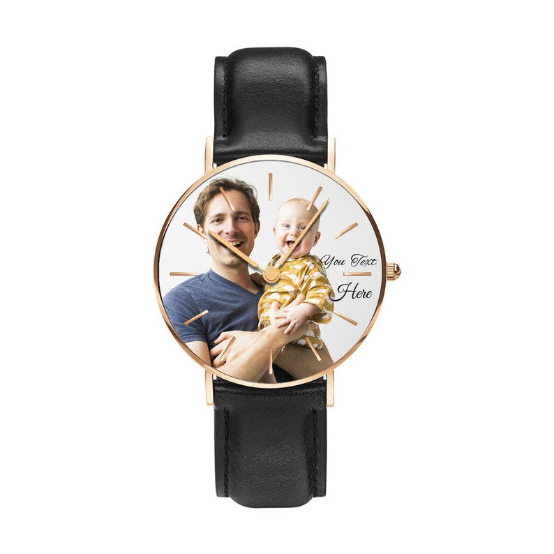 May include: A wristwatch with a black leather strap and a rose gold-tone case. The watch face features a custom photograph of an adult holding a baby, with thin rose gold-tone hour markers and hands. The text "You Text Here" is printed in black.