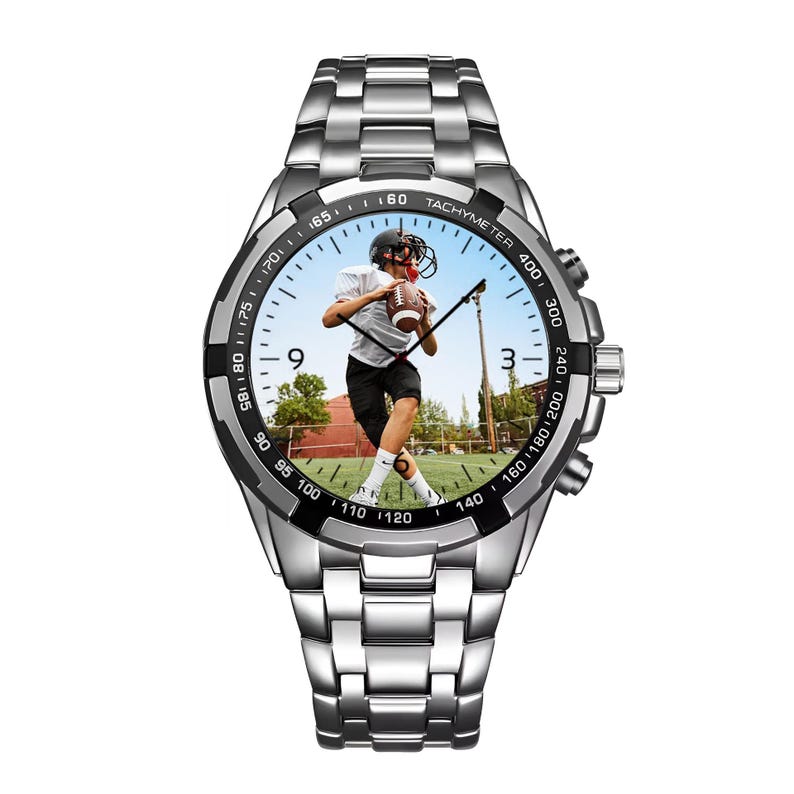 K&ouml;nnte beinhalten: Eine silberfarbene Armbanduhr aus Edelstahl mit einer schwarzen Tachymeter-L&uuml;nette und einem individuellen Zifferblatt, das ein Foto eines Footballspielers in wei&szlig;em Trikot und schwarzer Hose mit einem Football auf einem gr&uuml;nen Feld zeigt.