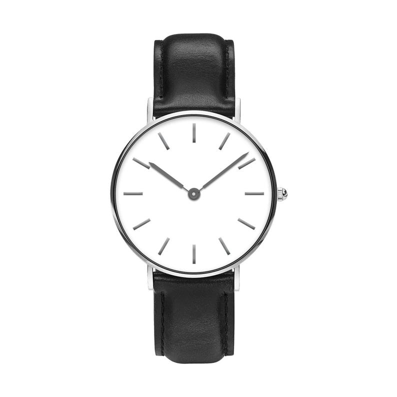 May include: A wristwatch featuring a round silver-tone case and a clean white dial with thin black hour markers. The watch has two slender black hands and is attached to a smooth black leather strap with visible stitching along the edges.