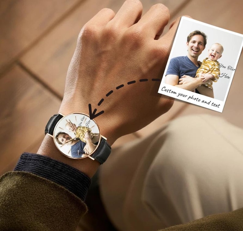 May include: A round analog wristwatch with a black leather strap and a gold-tone case. The watch face features a custom printed photograph of a person holding a baby. A dashed arrow points from a separate photo print to the watch face.