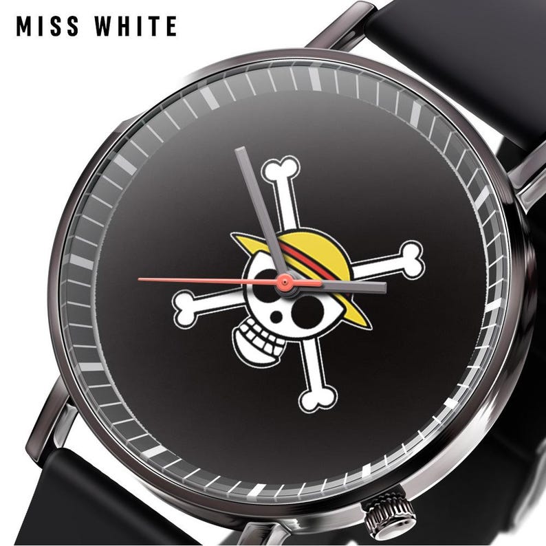 Pode incluir: Um rel&oacute;gio de pulso preto com mostrador redondo apresentando o texto MISS WHITE no canto superior esquerdo. O mostrador exibe um gr&aacute;fico de caveira e ossos cruzados em branco usando um chap&eacute;u de palha amarelo. Ponteiros cinzentos e ponteiro vermelho.
