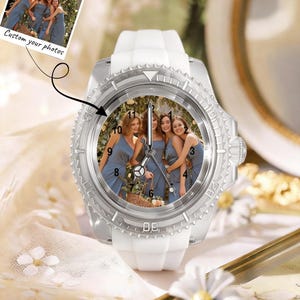 May include: A wristwatch with a white silicone strap and a silver-toned bezel featuring a custom photograph on the dial. The watch face displays a group of four people in blue dresses and includes black hour markers and silver hands. Text reads Custom your photos.
