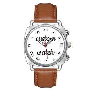 May include: A wristwatch with a silver square case, a white dial featuring black Roman numerals, and the text "custom watch" in black script. The watch has silver hour, minute, and red second hands, and a smooth brown leather strap.