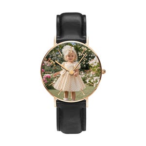 Puede incluir: Un reloj de pulsera con correa de cuero negro y caja circular en tono oro rosa. La esfera del reloj presenta una impresi&oacute;n fotogr&aacute;fica personalizada de un ni&ntilde;o peque&ntilde;o con un vestido color crema y un lazo a juego en un jard&iacute;n.