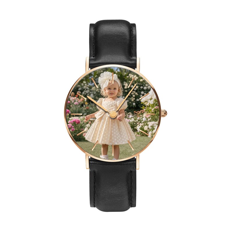 Puede incluir: Un reloj de pulsera con correa de cuero negro y caja circular en tono oro rosa. La esfera del reloj presenta una impresi&oacute;n fotogr&aacute;fica personalizada de un ni&ntilde;o peque&ntilde;o con un vestido color crema y un lazo a juego en un jard&iacute;n.