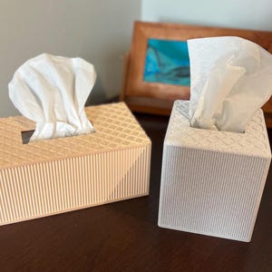 May include: A rectangular light peach tissue box cover and a square white tissue box cover, both featuring a textured diamond pattern on the top surface and vertical ribbed detailing on the sides, each holding a white tissue.