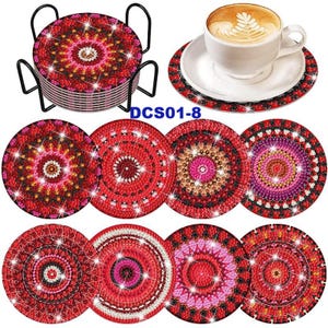 Puede incluir: Conjunto de ocho posavasos rojos, blancos y negros con un dise&ntilde;o de mandala. Los posavasos est&aacute;n hechos de un material brillante y tienen un dise&ntilde;o en relieve. Los posavasos est&aacute;n dispuestos en c&iacute;rculo alrededor de una taza de caf&eacute;.