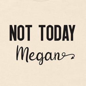 Può includere: T-shirt color crema con la scritta "NOT TODAY" in grassetto e maiuscolo nero, e il nome "Megan" in corsivo. La maglietta ha girocollo, maniche corte ed è realizzata in materiale morbido.