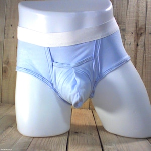 Peut inclure: Sous-vêtements bleu clair avec une ceinture élastique blanche. Le design comprend une poche et est présenté sur un mannequin. Le tissu semble être un mélange de coton doux.