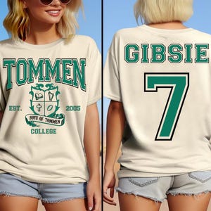 Puede incluir: Camiseta color crema con el texto "TOMMEN" en letras verdes, un escudo y "EST. 2005". La parte trasera de la camiseta muestra "GIBSIE" y el número "7" en verde con contorno negro. La camiseta forma parte de una colección temática universitaria.