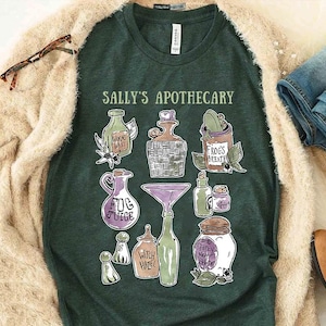 May include: Dark green t-shirt with the text "SALLY'S APOTHECARY" and illustrations of potion bottles and jars. The shirt is surrounded by a beige cardigan, blue jeans, and brown boots.