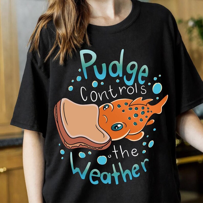 a woman wearing a t - shirt that says pudge controls the weather
