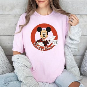 a woman wearing a pink mickey mouse shirt