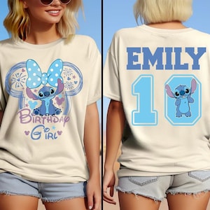 May include: Cream-colored t-shirt featuring a cartoon character design. The front displays a blue character with a bow, the text "Birthday Girl", and a Mickey Mouse-inspired outline. The back has the name "EMILY", the number "10", and the same character.