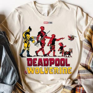 a deadpool and wolverine t - shirt sitting on top of a pile of clothes