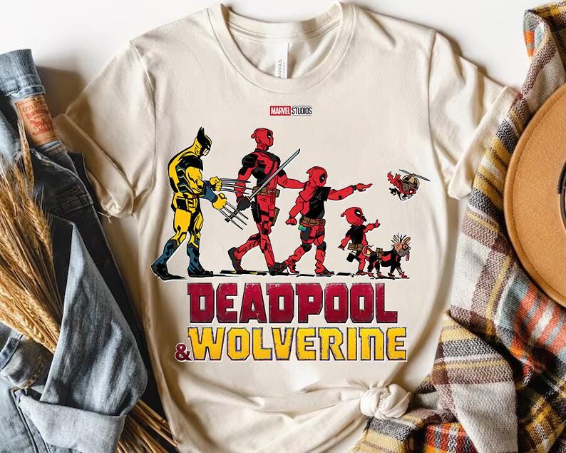 a deadpool and wolverine t - shirt sitting on top of a pile of clothes