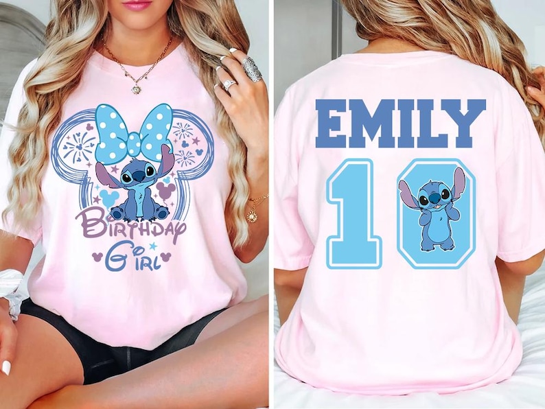 May include: Pink t-shirt featuring a blue cartoon character with a large bow, surrounded by a Mickey Mouse-shaped design. The front says "Birthday Girl." The back has the name "EMILY" and the number "10" with a matching cartoon character.
