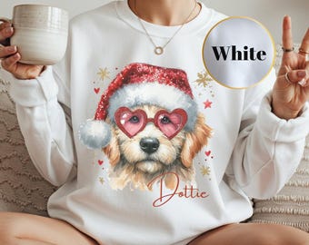 Può includere: Felpa bianca con un'illustrazione ad acquerello di un golden retriever con cappello di Babbo Natale e occhiali da sole a forma di cuore. Il nome del cane, "Dottie", è scritto in rosso. La parola "White" è in un cerchio.
