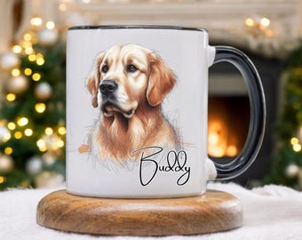 Op de afbeelding: Witte keramische mok met een zwarte handgreep en rand, met een gedetailleerde illustratie van een golden retriever hond. De naam van de hond, "Buddy", is in cursief geschreven. De mok staat op een houten onderzetter.