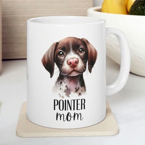 May include: White ceramic mug with a brown and white pointer dog illustration. The mug has a black handle and the text "POINTER MOM" printed on the front.