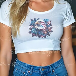 May include: White cropped t-shirt with a graphic of an American bald eagle with stars and stripes, surrounded by blue roses.