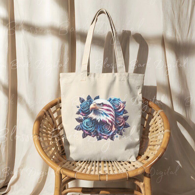 May include: A white canvas tote bag with a blue, red, and white American flag eagle design surrounded by blue roses. The eagle's head is facing the left side of the bag.