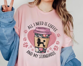 May include: Pink t-shirt with a coffee cup and a poodle graphic. The text on the shirt reads "All I need is coffee and my standards".