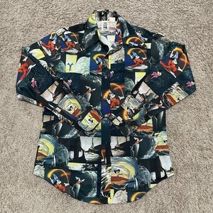 May include: A long-sleeved button-up shirt with a black background and a colorful pattern of Mickey Mouse as the Sorcerer's Apprentice from Fantasia. The shirt has a button-down collar and a button-up front.