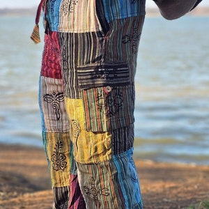 Może przedstawiać: Wielokolorowe spodnie patchworkowe z haftowanymi detalami. Spodnie mają luźny krój i sznurek do regulacji w pasie.