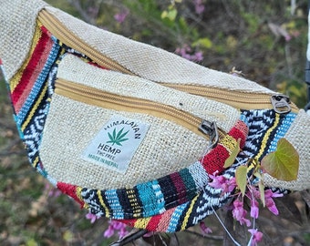 May include: A beige hemp fanny pack with a colorful woven trim and a zipper closure. The pack has a label that reads "Himalayan Hemp THC Free Made in Nepal".