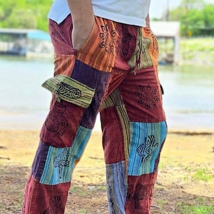 Può includere: Pantaloni patchwork con un design geometrico colorato. I pantaloni hanno una vita con coulisse e sono realizzati in un tessuto morbido e confortevole.