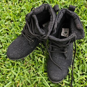 Pode incluir: Um par de botas de cano baixo de lona preta com cadar&ccedil;os pretos. As botas t&ecirc;m um logotipo de folha verde com o texto "PURE HEMP" no lado.