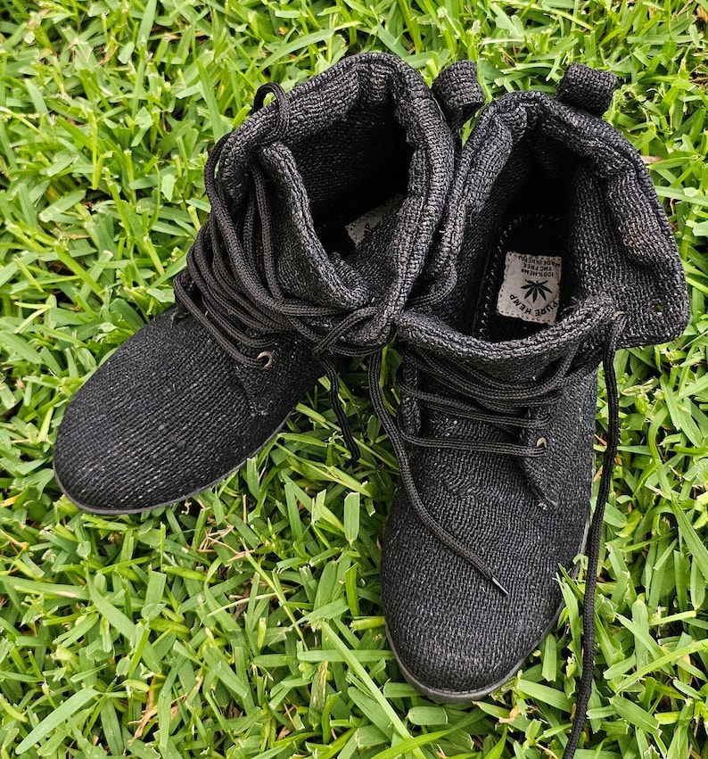 Pode incluir: Um par de botas de cano baixo de lona preta com cadar&ccedil;os pretos. As botas t&ecirc;m um logotipo de folha verde com o texto "PURE HEMP" no lado.