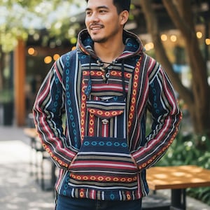 May include: A patterned hoodie with a front pocket and drawstring hood. The design features vertical stripes in blue, red, and white. The person is wearing blue jeans.
