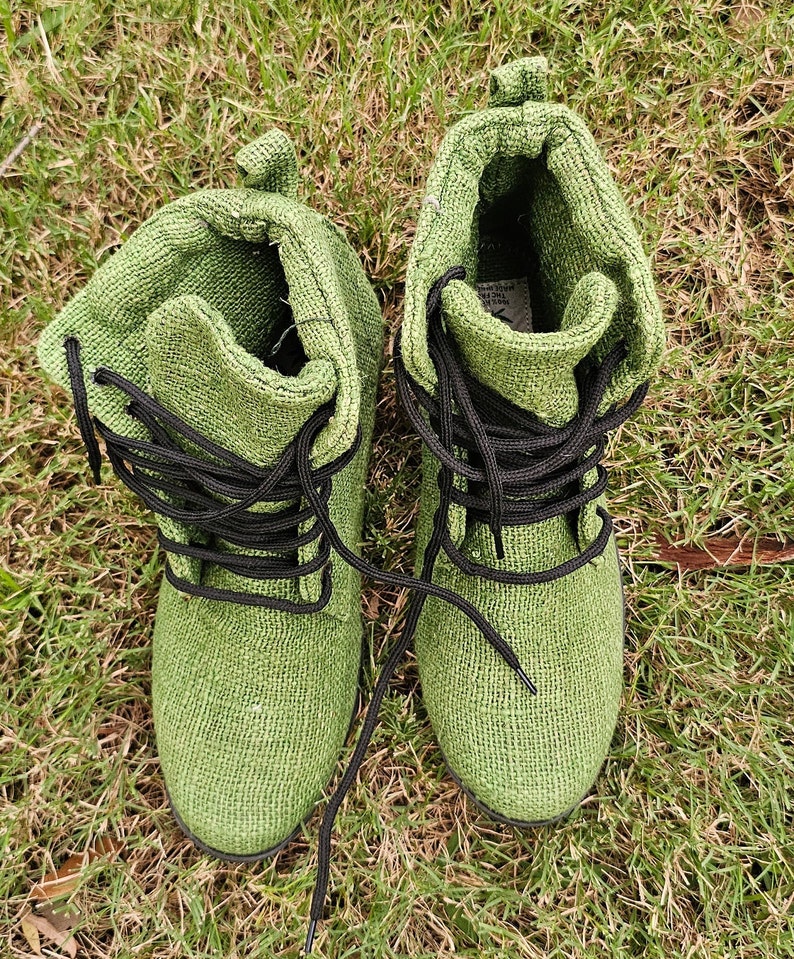 Pode incluir: Um par de botas de lona verde com cadar&ccedil;os pretos. As botas est&atilde;o sobre um leito de grama verde.