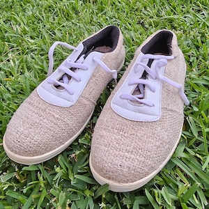 Pode incluir: Dois pares de sapatos de lona bege com cadar&ccedil;os brancos. Os sapatos t&ecirc;m uma parte superior de tecido texturizado e uma sola de borracha branca.