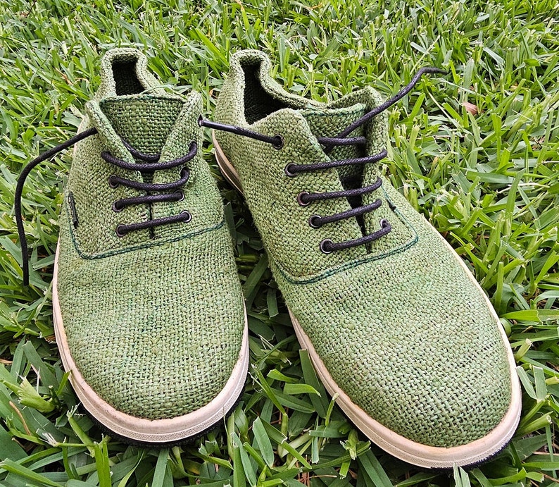 Pode incluir: Um par de sapatos de lona verde com cadar&ccedil;os pretos. Os sapatos t&ecirc;m uma sola branca e s&atilde;o feitos de um tecido tecido.