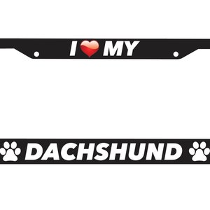 Puede incluir: Marco de matrícula negro con texto blanco que dice "Me encanta mi Dachshund" con un corazón rojo y huellas de patas a cada lado.