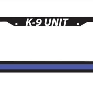 Puede incluir: Marco de matrícula negro con el texto "K-9 UNIT" en blanco. El marco tiene una franja azul en la parte inferior y está diseñado para adaptarse a una placa de matrícula estándar. El marco es rectangular con esquinas redondeadas.