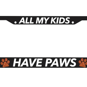 Puede incluir: Marco de matrícula negro con texto blanco que dice "All My Kids Have Paws" y dos huellas de patas marrones.
