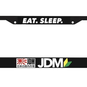 Puede incluir: Marco de matrícula negro con texto blanco que dice "EAT. SLEEP. JDM" y una bandera japonesa con el texto "JDM" y "日本の国内市場" en japonés.