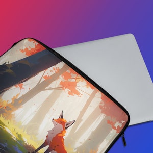 Peut inclure: Une housse d'ordinateur portable avec une illustration color&eacute;e d'un renard dans un d&eacute;cor de for&ecirc;t. La housse est noire avec une fermeture &eacute;clair.