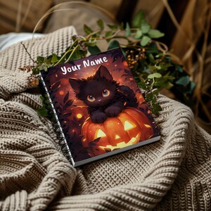 Könnte beinhalten: Eine schwarze Katze mit gelben Augen sitzt in einem geschnitzten orangefarbenen Kürbis. Der Kürbis hat ein gruseliges Gesicht mit einem breiten Grinsen und leuchtenden Augen. Der Hintergrund ist ein dunkler Wald mit leuchtenden Lichtern. Der Notizbuchumschlag sagt "Your Name".