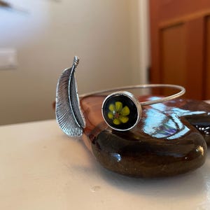 Flower and leaf! Adjustable Silver bracelet. Accented with a captivating yellow flower set on a blue fused glass backing.